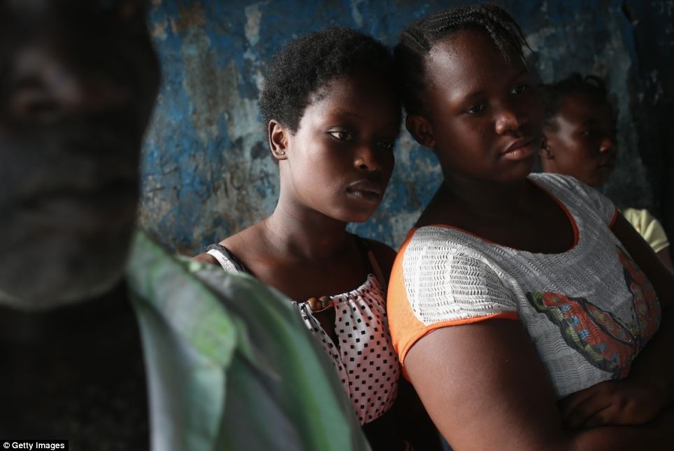 Vẻ mặt căng thẳng của những người phụ nữ khi cha của họ chuẩn bị tới trạm cách ly người nghi nhiễm Ebola.