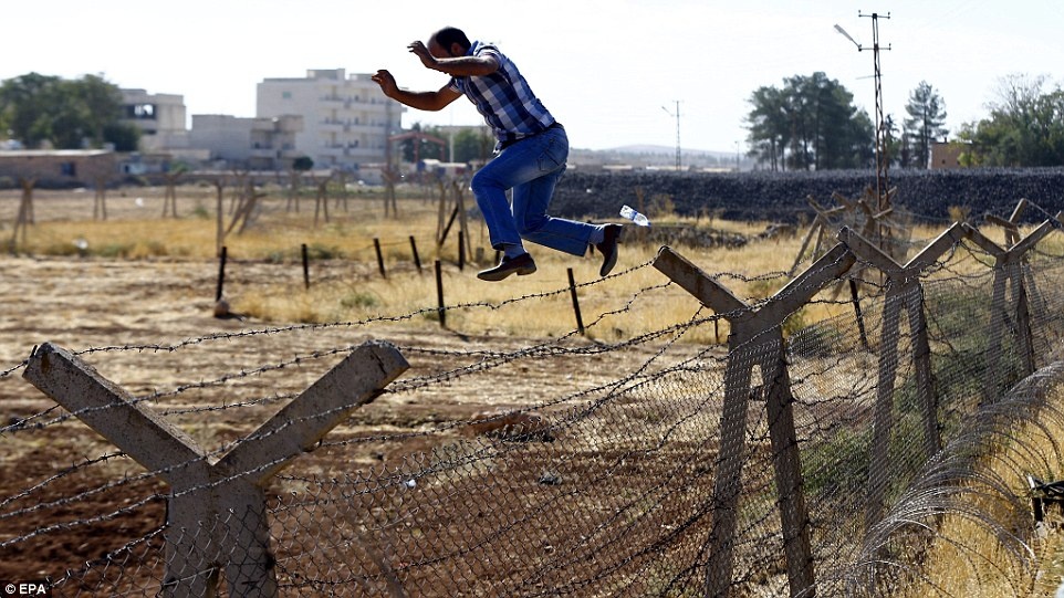 Một người đàn ông trèo lên cột bê tông rồi nhảy sang phía Thổ Nhĩ Kỳ. Ảnh: EPA