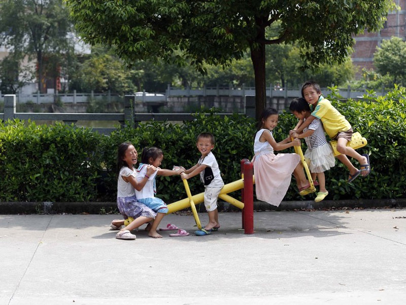 6 đứa con chơi trò chơi bập bênh. Yang chỉ đăng ký hộ khẩu cho 3 trong số 7 đứa. Không có hộ khẩu, các con của ông không thể đến trường.