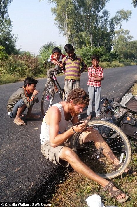 Người dân địa phương nhìn chàng trai trẻ chăm chú khi anh dừng lại để sửa xe ở bang Uttar Pradesh, Ấn Độ. Trong cuộc hành trình, Walker phải vá chiếc xe đạp “Old Geoff” hơn 250 lần.