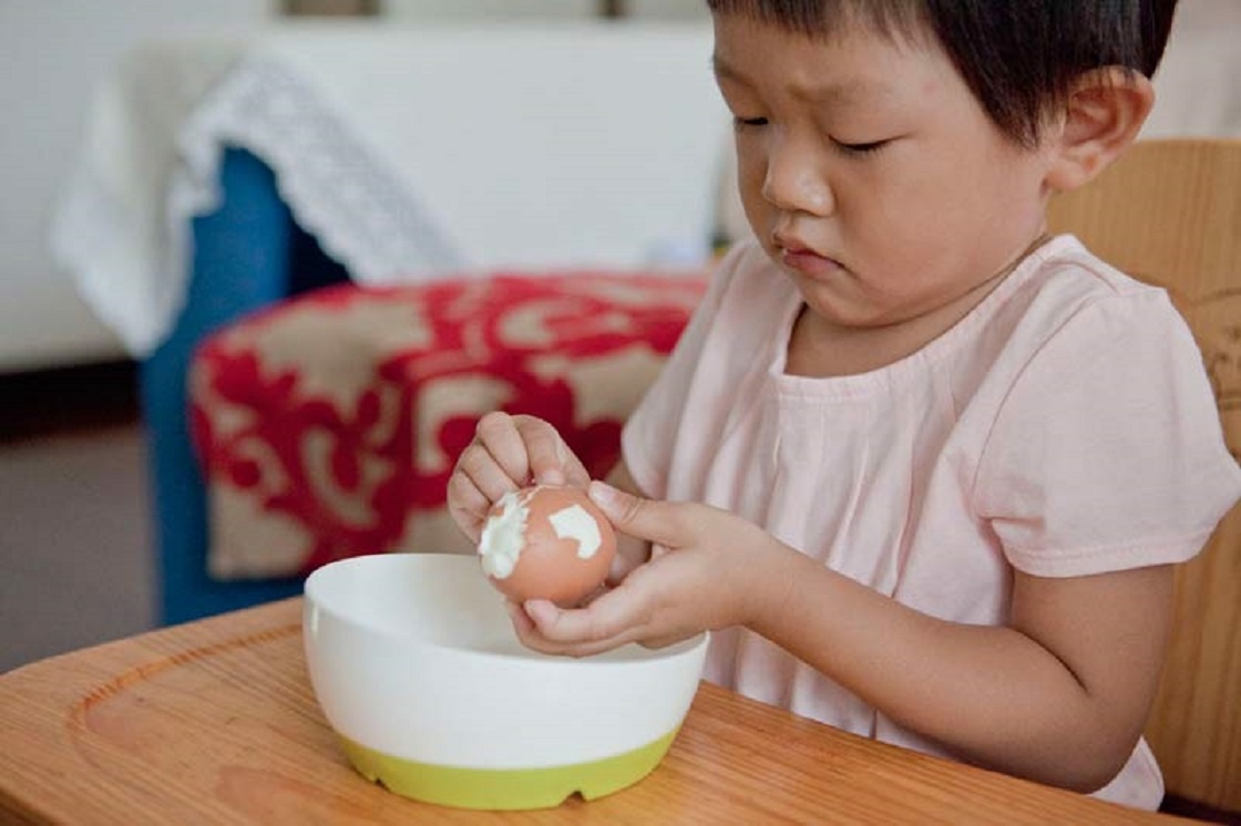 Yixin đang bóc vỏ trứng. Bé cũng có thể tự mặc quần áo.