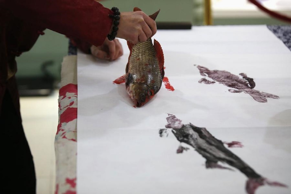 Anh nhúng cá thật vào mực rồi đặt lên bản vẽ.