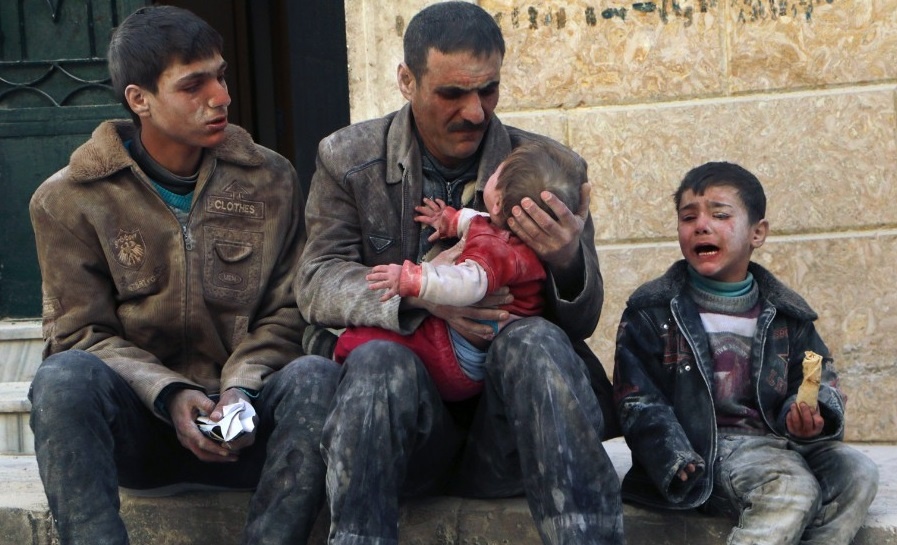 Người đàn ông Syria bế một đứa trẻ sống sót sau cuộc không kích của lực lượng trung thành với chính phủ