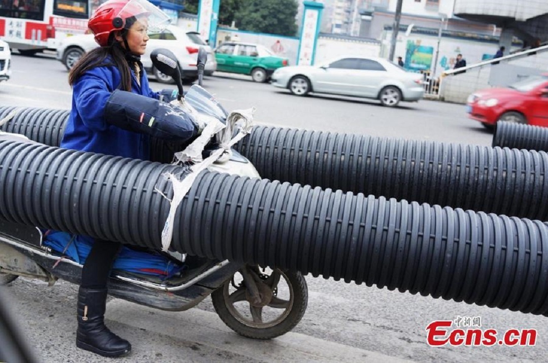 Người phụ nữ buộc hai ống lớn và dài hai bên xe, gây khó khăn cho việc điều khiển.