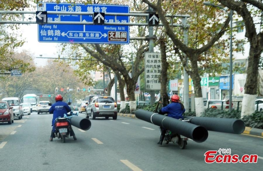 Hai người chở đồ cồng kềnh cản trở giao thông trong thành phố.