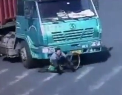 Nguoi di xe dap thoat chet khi lot vao gam xe tai hinh anh