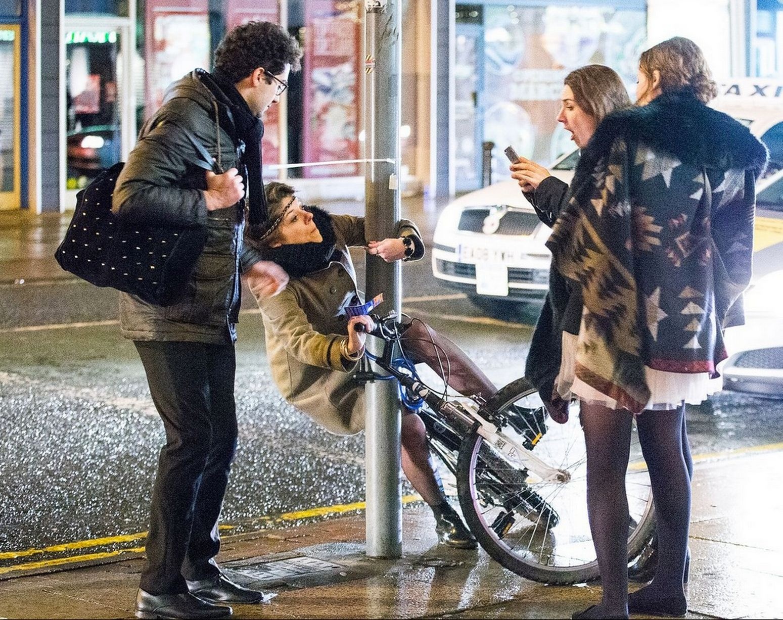 Dù bám vào cột sắt, người phụ nữ vẫn không thể giữ thăng bằng khi ngồi lên xe đạp.