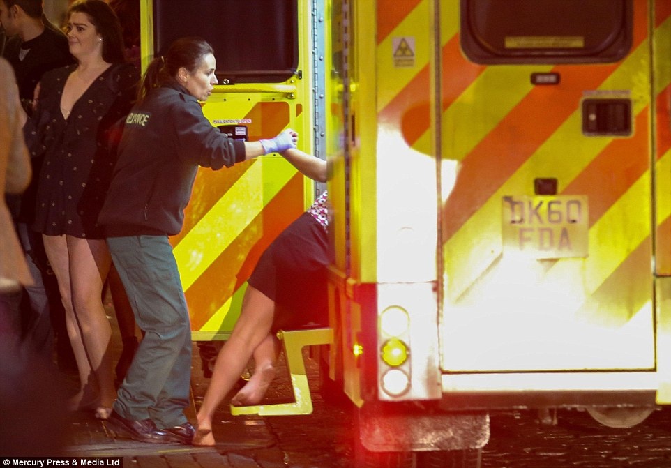 Nhân viên y tế nắm tay một phụ nữ khi cô ngã vào xe cứu thương tại thành phố Liverpool. Ảnh: