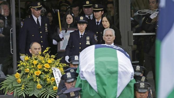 Nhóm cảnh sát khiêng quan tài của Wenjian Liu ra khỏi nhà tang lễ. Vợ của Liu ôm di ảnh của chồng ở phía sau quan tài. Ảnh: EXE