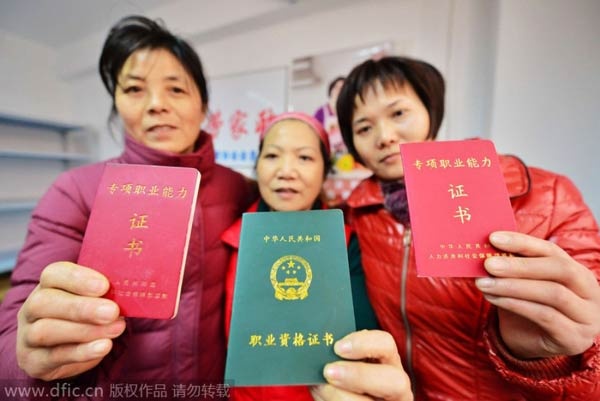 3 phụ nữ giơ chứng chỉ nghề bảo mẫu trong một trung tâm giới thiệu việc ở Thượng Hải.