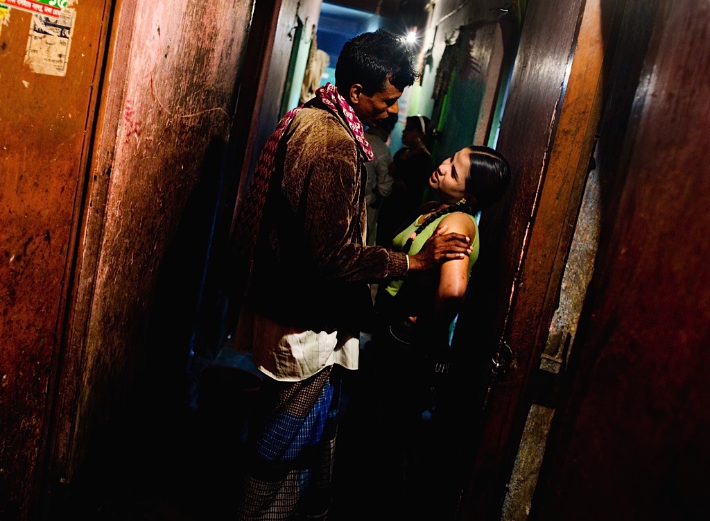 Một gái bán dâm mặc cả với khách hàng trong hành lang tối của nhà thổ.