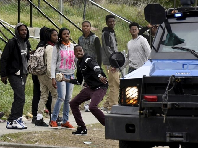 Một thanh niên cầm đá chuẩn bị ném vào ôtô cảnh sát. 