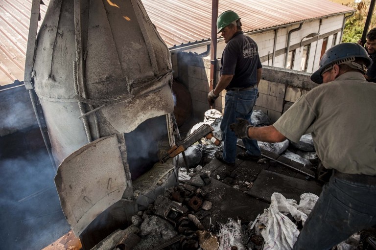 Công nhân ném những mẩu kim loại vào lò để nung.