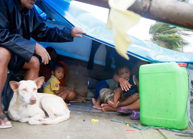 Người dân dựng lều tạm cạnh bức tường bê tông để trú khi bão Koppu đổ bộ gây gió lớn và mưa. Ảnh: AP