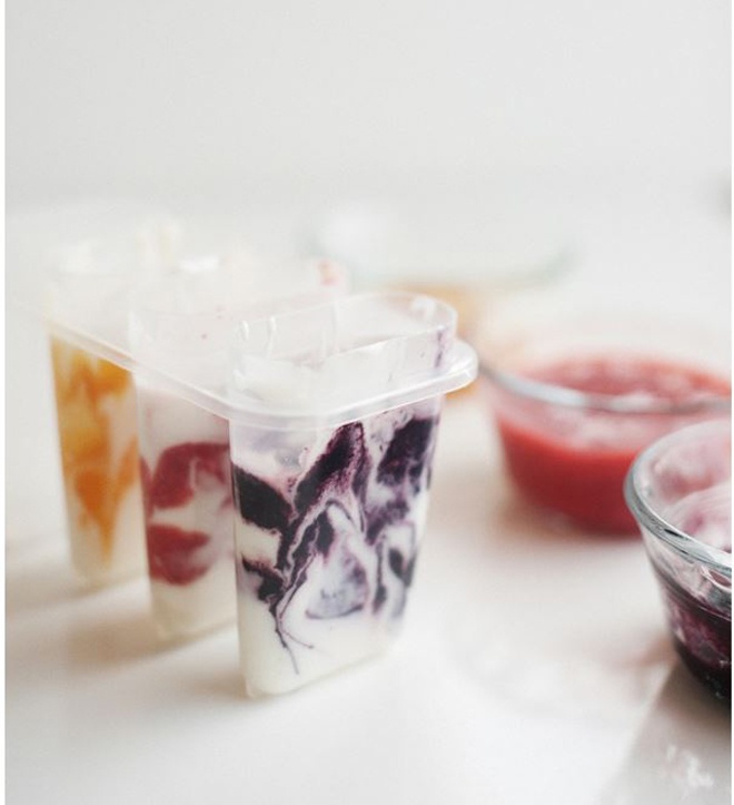 Bước 2: Cho từng thìa hỗn hợp sữa chua đã trộn sẵn, cùng từng thìa nước cốt dâu tây, đào, dâu tằm hoặc việt quất vào trong khuôn … Tùy theo sở thích mà bạn có thể cho cùng lúc nhiều quả vào chung 1 khuôn hoặc cho riêng thành từng loại. 