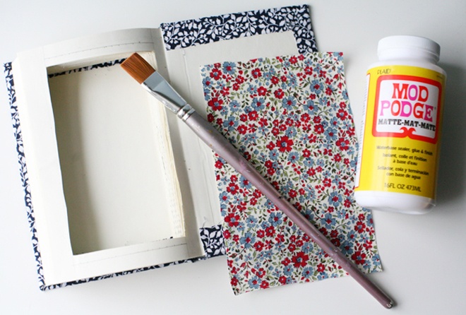 Canh và cắt miếng vải lót theo kích thước của bìa sách. Dùng keo dán 2 miếng vải này lên 2 phần bên của quyển sách.