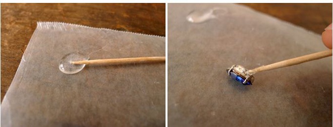 Bước 1: Phết 1 ít keo lên giấy sáp, sau đó dùng tăm quết keo đều khắp mặt sau viên đá crystal và ấn vào giấy sáp.