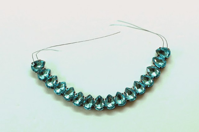 Đầu tiên, luồn 2 sợi dây đồng vào từng hạt đá crystal hình quả lê màu xanh ngọc để tạo thành 1 chuỗi dây gồm 16 viên đá. Nhớ chừa 2 đầu dây để dễ thao tác về sau. 5 Tiếp đó, lần lượt dùng dây đồng nối các hạt crystal còn lại giống với ảnh minh họa.
