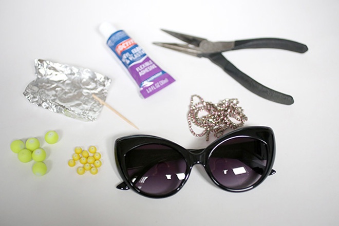  Nếu cũng muốn tự tay làm nên 1 cặp kính mắt mèo thật ấn tượng cho riêng mình, bạn hãy sưu tầm các nguyên vật liệu sau: 1 cặp kính mắt mèo có phần khung rộng, vài dây hạt đá crystal màu hồng, các hạt gỗ hoặc hạt cườm nhựa tròn màu neon (xanh, vàng hay tùy sở thích của bạn), keo dán, giấy bạc, vài cây tăm và 1 cây kềm.