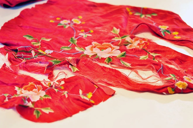 Đầu tiên, hãy tập hợp đầy đủ những nguyên vật liệu cần thiết sau: 1 chiếc túi nhỏ màu đen (hoặc các màu khác tùy ý) kiểu dáng đơn giản, 1 mảnh vải thêu hoa lá rực rỡ theo ý thích của bạn (nên chọn loại hoa to bản để dễ thao tác sau này), 1 cây kéo, vài cuộn chỉ màu, vài cây cọ và 1 lọ keo dán vải.