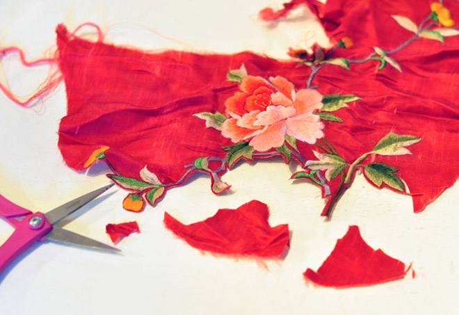 Bắt tay vào việc bằng cách chọn các họa tiết thêu hoa ưng ý trên vải, sau đó khéo léo dùng kéo cắt phần họa tiết này ra khỏi miếng vải.