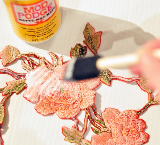 Dùng cọ phết keo vào mặt sau của hoa lá vừa cắt, sau đó dán chúng lên ví theo những vị trí đã định trước.