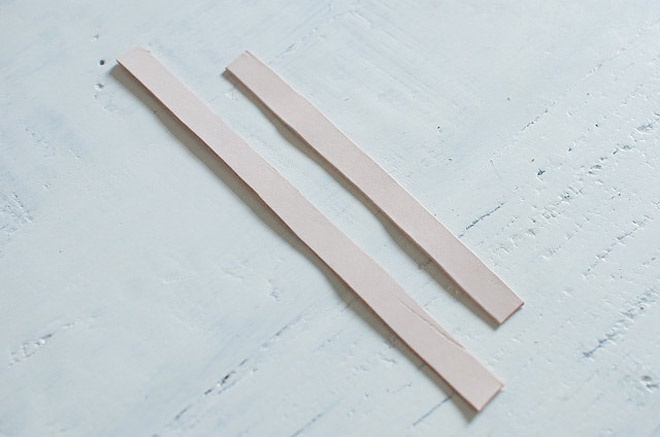 Bước 2: Dùng thước đánh dấu, sau đó cắt 2 mảnh vải da có chiều rộng khoảng 1,5 cm, với chiều dài chênh lệnh nhau. 1 mảnh có chiều dài vừa với cổ tay bạn, 1 mảnh khác ngắn hơn dùng để làm nơ.