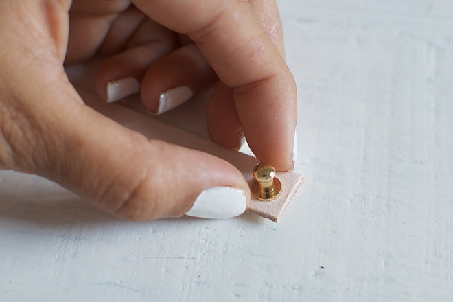 Bước 4: Gắn một đầu chiếc nút mạ vàng vào lỗ đã bấm để tạo thành kiểu khóa đơn giản như trong hình minh họa.