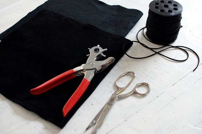 Đầu tiên, hãy sưu tầm đầy đủ nguyên vật liệu sau: 1 chiếc kéo, 1 cây kềm bấm lỗ, 1 miếng vải da lớn hình chữ nhật và 1 cuộn dây da sợi mảnh.