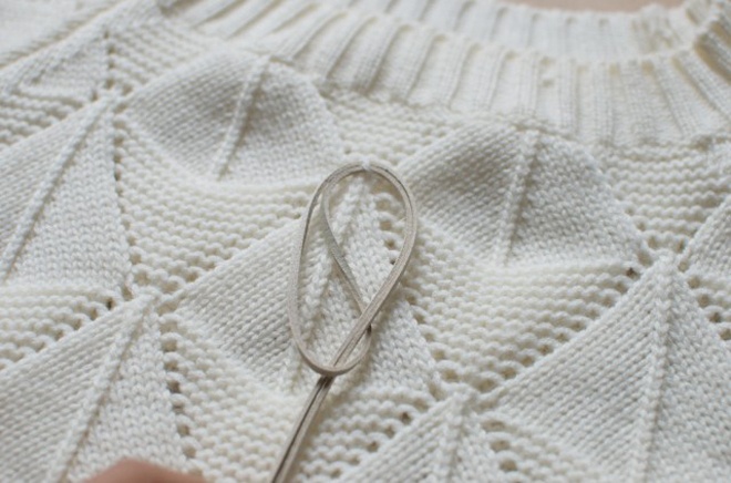 Luồn sợi dây da vào đường nối trên chiếc áo len, ở phần gần cổ áo như hình minh họa rồi thắt nút lại.