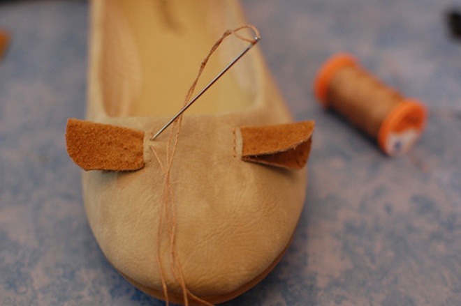 Dùng dao rọc 2 đường chéo bên trên bề mặt đôi giày. Gấp đôi miếng vải da nhỏ, cho phần vải da vào bề mặt giày vừa bị cắt và dùng kim may lại để tạo thành 2 đôi tay chuột.