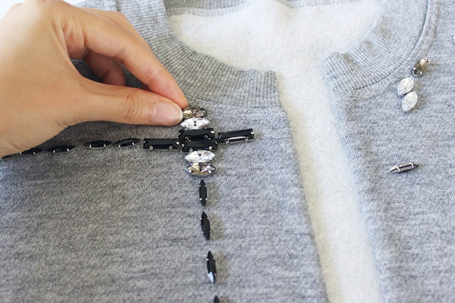 Cho một ít keo ra bìa giấy trắng, dùng tăm phết keo vào phần mặt sau hạt đá và gắn các hạt đá lên áo theo những đường kẻ đã định hình trước đó.