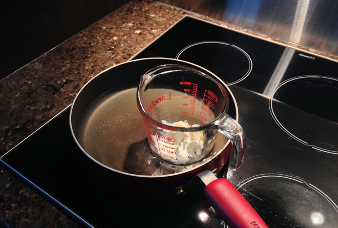 Cho nước vào gần 1/2 nồi, sau đó đặt cốc thủy tinh bên trong nồi và bắt đầu đun nóng. Nên bật bếp lửa lớn vì nhiệt độ cao làm tan chảy các nguyên liệu tốt hơn. Thỉnh thoảng dùng muỗng khuấy cho đến khi nguyên liệu nóng chảy và trộn đều vào nhau.