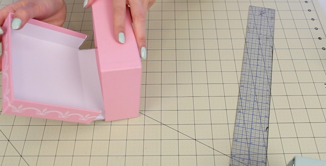 Bước 2. Úp phần bìa chiếc nắp vừa cắt vào một cạnh bên của hộp giấy và thử gấp lại, điều chỉnh nếp cắt cho đến khi  phần nắp và hộp đã vừa khít với nhau.