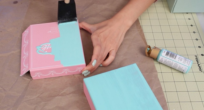 Bước 3. Dùng cọ phết sơn arcylic lên toàn bộ mặt ngoài của hộp. Để không lưu lại vết cọ, bạn nên dùng một miếng bột biển thay vì cọ có lông như bình thường. Cũng không nên chọn màu quá tương phản với màu sẵn có của chiếc hộp, ví dụ màu trắng sẽ khó che được chữ đen in trên hộp, thay vào đó thử dùng màu tím hoặc xanh. Chờ lớp sơn đầu khô trong khoảng 15 – 20 phút rồi tiếp tục phết thêm 2 – 3 lớp sơn tương tự.