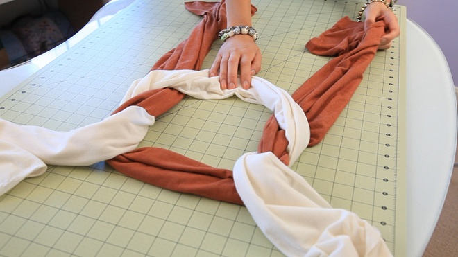 Nối 2 chiếc khăn lại với nhau bằng cách lấy 2 đầu chiếc khăn trắng luồn qua chiếc khăn màu nâu đậm.