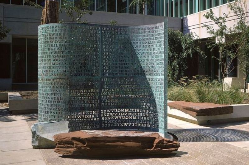 2. Kryptos: Nằm ngay trước trụ sở Cục tình báo trung ương Mỹ CIA ở Langley, Virginia, Kryptos là một tác phẩm đặc biệt được nhà điêu khắc nổi tiếng người Mỹ Jim Sanbom tạo tác bằng đồng và đá vào năm 1990. Tác phẩm này bao gồm bốn tấm bằng đồng và ba phần đã được giải mã. Thông điệp đầu tiên có nội dung như sau: “Giữa bóng tối huyền ảo và sự thiếu ánh sáng, ẩn chứa một sắc thái ảo giác