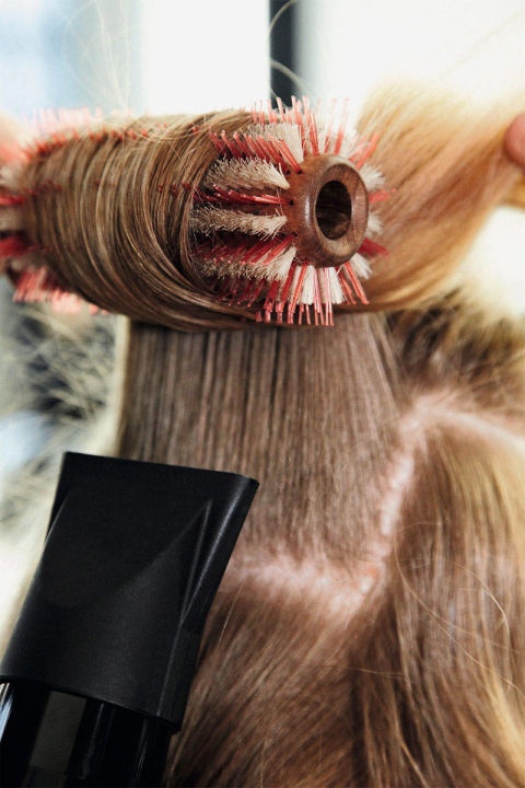 Bước 2: Bắt đầu từ phía sau, thực hiện với từng phần tóc theo chiều từ chân tóc đến ngọn tóc. Đặt một chiếc lược tròn dưới gốc tóc, nâng lược lên đến một góc 90 độ và kéo lược thẳng đến đuôi tóc. Để tạo độ dày tối đa, cuộn cả lọn tóc xung quanh lược. Sau khi sấy nóng nhanh trong vài giây, giữ dáng tóc bằng cách chuyển sang sấy lạnh. Nhẹ nhàng gỡ lược ra và giữ chặt lọn tóc cuốn bằng ghim kẹp.