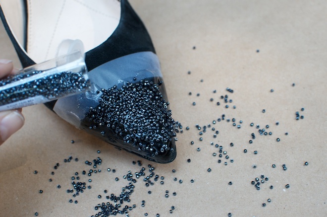 Bước 3. Rắc hạt cườm lên vùng mũi giày. Cẩn thận rắc đều và dùng tay ấn các hạt cườm ngập sâu vào trong lớp keo. Cần chắc chắn các hạt cườm đã phủ ngập bề mặt và không để lộ lớp da giày bên dưới.