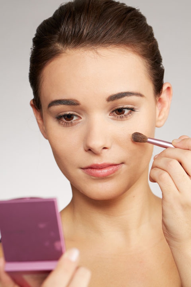 Bước 4. Hoàn chỉnh lớp phủ với phấn bột. Chỉ nên chọn phấn pigmented powder gần với tone màu da của bạn.  Đây chính là bí quyết để giữ lớp trang điểm bền màu suốt cả ngày, vì pigmented powder là loại phấn bột có độ dính cao, tạo màu sắc tinh tế và không để lại vệt hay vết loang trên da trong điều kiện nắng nóng, đổ mồ hôi… Đặc biệt, bạn cần tránh xa phấn phủ không màu (translucent powder) vì chúng sẽ làm các tì vết trên da, bao gồm các nốt mụn, trở nên bóng và dễ thấy hơn.