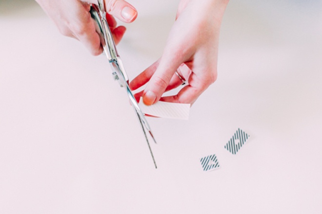 Phết đều một lớp sơn bóng lên toàn bộ móng tay. Trong thời gian chờ sơn khô, bạn nên cắt 1 đoạn băng keo rồi gấp đôi. Dùng kéo cắt phần gấp đôi để tạo thành hình trái tim như ảnh minh họa. 