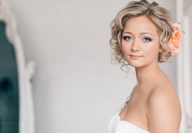 Cài thêm hoa vải bản to, kết hợp những lọn tóc uốn xoăn và tạo độ phồng làm dịu mái tóc ngắn cá tính thường ngày, để cô dâu thêm ngọt ngào, quyến rũ.