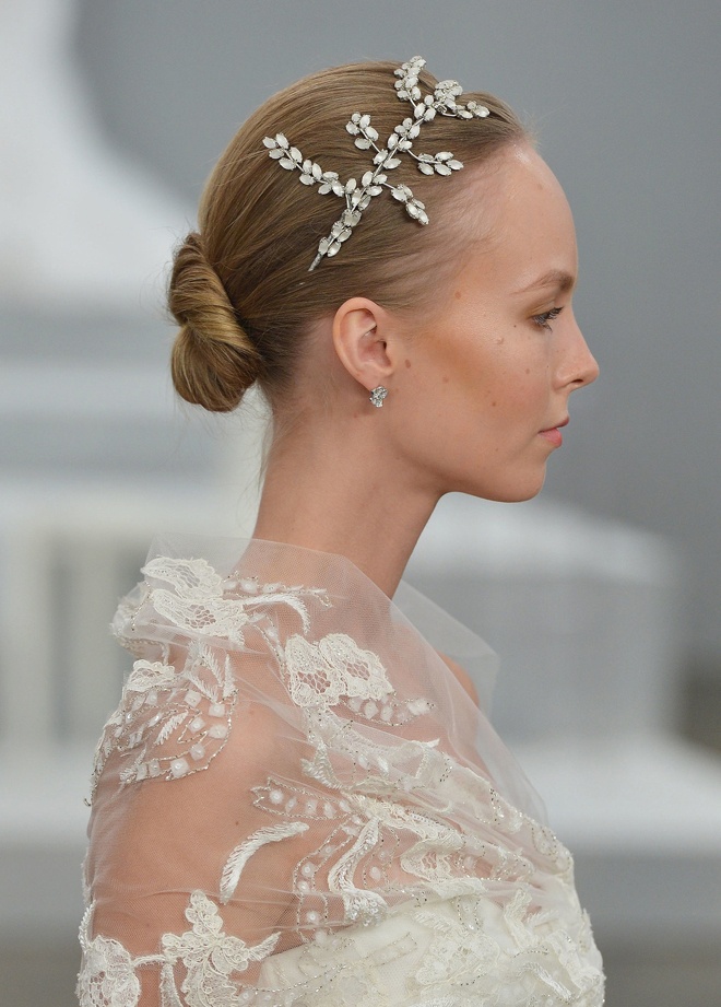 Đầu tiên là buộc đuôi gà, vuốt gel cố định nếp và xoắn phần đuôi tóc. Sau đó cuộn tròn và dùng kẹp tăm cố định. Cuối cùng cài thêm nơ, hoa, vòng hoa hoặc khăn cưới để tạo nên kiểu tóc búi “củ tỏi” rất năng động và sành điệu.