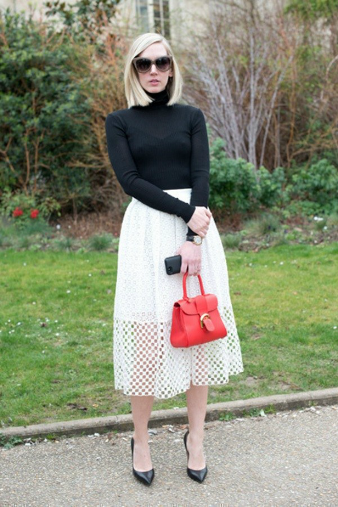 1. Kết hợp với chân váy midi: Chân váy midi trắng với áo len cổ lọ và giày cao gót cùng tông màu đen là một cách phối đồ khá an toàn. Chiếc túi xách màu đỏ chính là ‘‘vũ khí‘‘ giúp bộ trang phục này không trở nên quá nhàm chán và đơn giản.