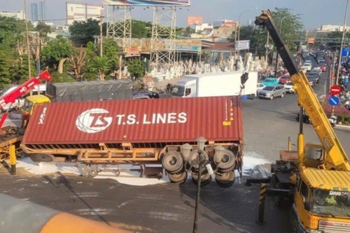 Xe container lat giua vong xoay o TP.HCM, son trang tran mat duong hinh anh