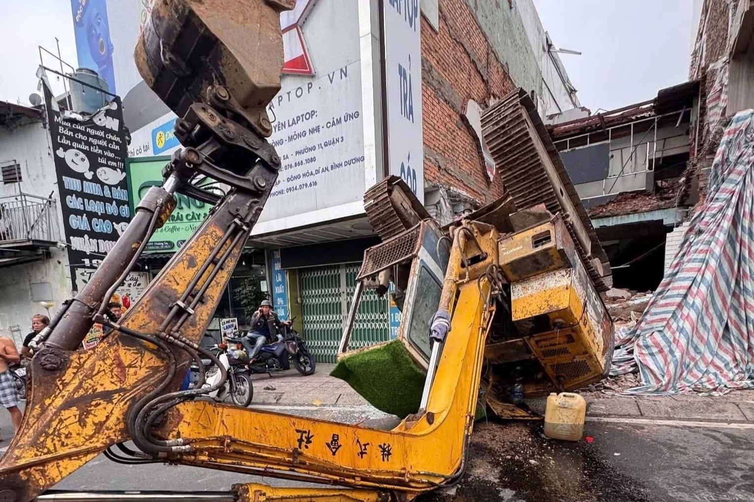 Tháo dỡ nhà, xe múc bất ngờ lật ngửa trên đường
