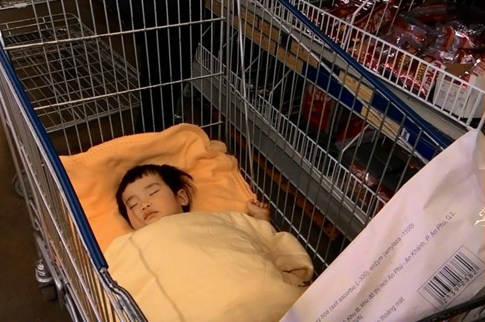 Tre em ngu tren xe day sieu thi khi bo me mua sam hinh anh