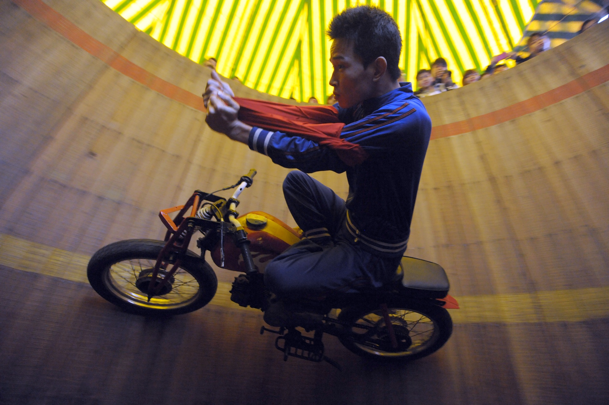 Chàng trai sinh năm 1991, Nguyễn Đức Thản biểu diễn động tác mặc áo trong khi hai chân xếp bằng trên bình xăng ở độ cao 3,5m khi xe di chuyển với tốc độ gần 50km/h.