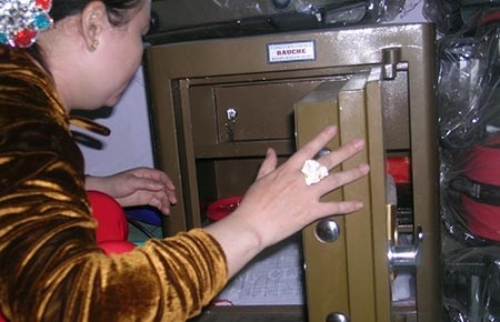 Chị Phạm Thị Ngọc Tuyết bên cạnh chiếc két sắt bị trộm.