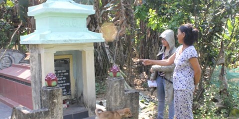 Bà Bình bên mộ chồng, một nạn nhân của nhóm cướp đêm 19/1/1980.